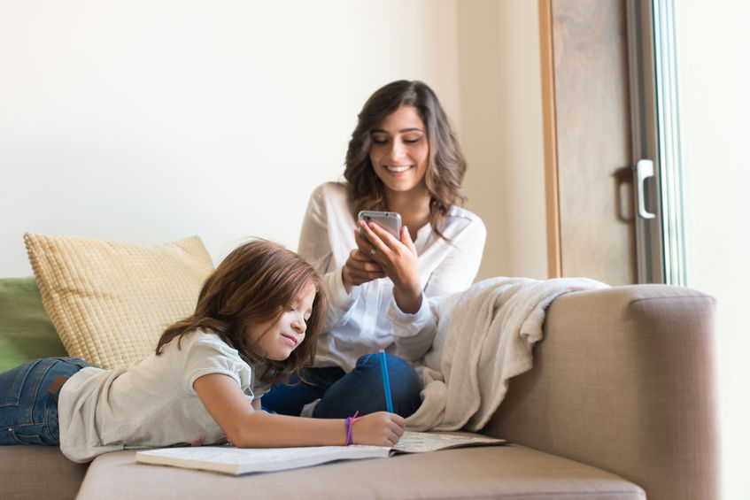 55370495 - little girl painting in the living room while mom is on internet
