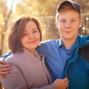 Mother and adult son in autumn park or forest in a sunny day. Happy family walking outdoors